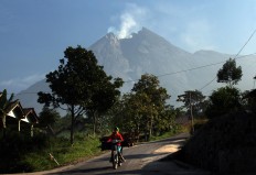 Mount Merapi spews smoke while a villager is seen carrying wood. JP/Boy T. Harjanto