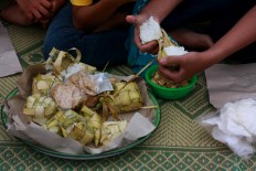 Digging in: A villager peels coconut leaves off the famous rice cake known as ketupat. JP/Maksum Nur Fauzan
