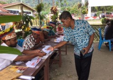 A voter collects a ballot paper from an election official wearing traditional Papuan dress, on June 27, 2018 at polling station TPS 005 in Awiyo subdistrict, Abepura district, Jayapura, to vote in the Papua gubernatorial election. JP/Nethy Dharma Somba