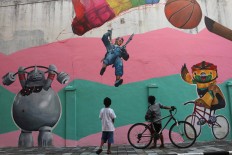 Two boys admire the mural in the Asian Games kampong in Surakarta, Central Java. JP/Maksum Nur Fauzan