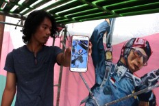 One of the artists shows a picture of his work on his phone. JP/Maksum Nur Fauzan