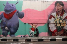 An artist paints Atung next to a picture of 1992 Olympic gold medalist Susy Susanti. JP/Maksum Nur Fauzan