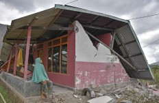 A woman sits in front of her partially collapsed house in Sembalun Bumbung village, Sembalun district, East Lombok. Antara/Ahmad Subaidi