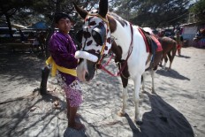 A man dressed in Javanese traditional costume holds his horse. JP/Boy T. Harjanto