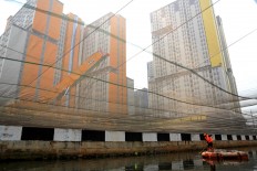 Going clean: A Jakarta Sanitation Agency worker removes waste from a polluted river in Kemayoran, Central Jakarta, on Friday, July 20, 2018. The Jakarta administration has covered the river, which runs next to the Kemayoran athletes village with a black net to contain the strong odor. JP/Seto Wardhana