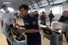 System maintenance: Officials from commuter train operator Kereta Commuter Indonesia (KCI) upgrade an electronic gate at Palmerah Station in Central Jakarta on Monday, July 23, 2018. KCI began maintenance work and upgraded its e-ticketing system on Sunday. JP/Dhoni Setiawan