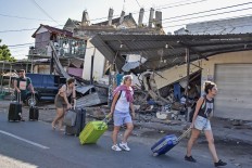 Foreign tourists drag their luggage in Pemenang district, North Lombok, on Monday Aug. 5, 2018. Antara/ Ahmad Subaidi