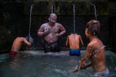 After finishing the ritual, the villagers wash the paint off their bodies at a spring. JP/Agung Parameswara