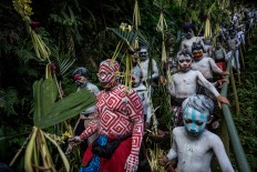 Young villagers walk around their village with their bodies painted. JP/Agung Parameswara