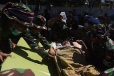 Military personnel lift an injured victim to a health tent at Tanjung Hospital in North Lombok on Tuesday Aug. 7, 2018. Antara/Zabur Karuru