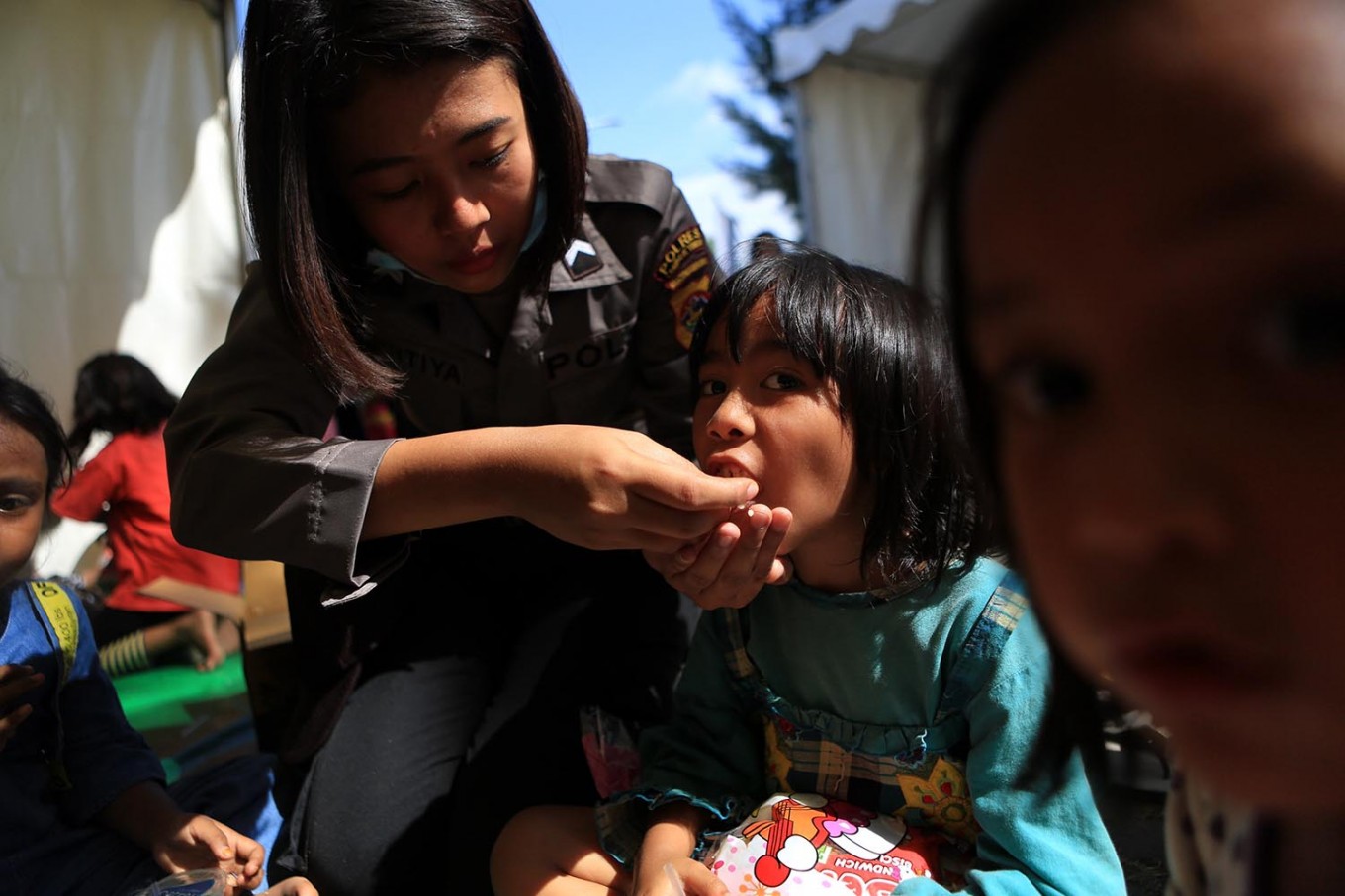 A police officer feeds a child victim during a Trauma Healing Program at a shelter in Supersemar field in Tanjung District, North Lombok. The propgram was aimed at helping children cope with trauma from the natural disaster. JP/Seto Wardhana