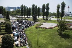 People use parasols while waiting in line for a show in Odaiba, Tokyo. JP/Rosa Panggabean