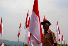 An elderly citizen looks at the red-and-white flag. JP/Maksum Nur Fauzan
