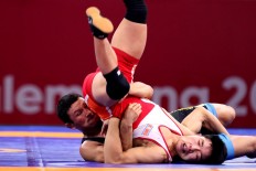 Get a grip: Kyrgyztan wrestler Kanybek Zholcubekov (left) controls his opponent from the People's Republic of Korea during men's Greco-Roman wrestling match. JP/ Seto Wardhana