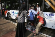 Volunteers help a person with disability on to a shuttle service in Jakarta. JP/Dhoni Setiawan