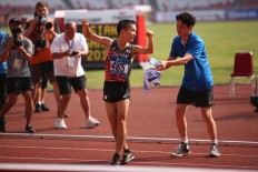 An official hands a bottled water to Japan’s Hiroto Inoue after the finish line in Jakarta. JP/P.J. Leo