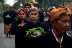 Takeaway: Men of the Bonokeling tribal community carry to their homes a traditional chicken soup called ambengan. JP/Kukuh Sukmana Hasan Surya