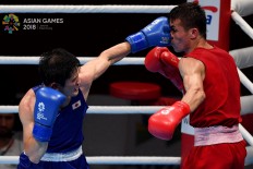 Japanese boxer Arashi Morisaka (left) attacks Hursand Imankuliyev of Turkmenistan in a men’s 60-kilogram match at the 2018 Asian Games at the Jakarta International Expo in Kemayoran, Central Jakarta, on Friday, August. 24. Inasgoc via Antara/Wendra Ajistyatama