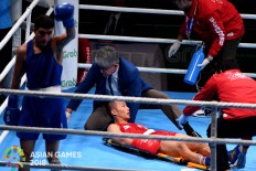 Filipino boxer Mario Fernandez (center) is treated by a doctor after being knocked down by Jaafar A Al Sudani of Iraq (left) during a 56 kg fight at the 2018 Asian Games at the Jakarta International Expo in Kemayoran, Central Jakarta, on Saturday, August. 25. Inasgoc via Antara/ Wendra Ajistyatama