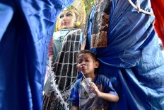 Having fun: A boy plays around completed ondel-ondel figures in Kramat Pulo, Central Jakarta. JP/David Caessarre