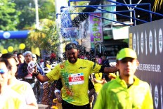 A splash of energy: A runner enjoys a splash of cold water as he completes his course at the 2018 Maybank Bali Marathon on Sept. 9 in Gianyar, Bali. 