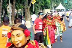 A cultural touch: A 2018 Maybank Bali Marathon runner pauses to take a photograph with a local performer wearing a mask depicting a Balinese shadow puppet character in Gianyar, Bali. The race showcases a variety of Balinese music and dance performances to entertain runners throughout the track.