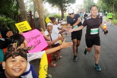 Young cheerleaders: Students from Klungkung village, Bali, cheer on runners on during the 2018 Maybank Bali Marathon on Sept. 9 as they approach the finish line.