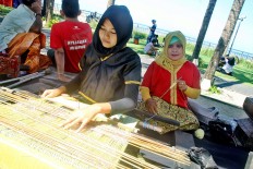 Women’s empowerment: Anita, a female entrepreneur, weaves tenun (traditional woven cloth from Lombok, West Nusa Tenggara) in a showcase during the race pack collection for the 2018 Maybank Bali Marathon on Sept. 8 in Taman Bhagawan, Tanjung Benoa, Bali. Anita is one of the recipients of  Maybank Indonesia’s women eco-weavers program, an initiative seeking to empower women through entrepreneurship, which the bank has been organizing since 2012.