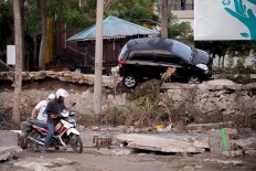 A man attempts to ride his motorcycle through the mud in Palu in Central Sulawesi on September 29, 2018, after a strong earthquake and tsunami struck the area. Nearly 400 people were killed when a powerful quake sent a tsunami barrelling into the Indonesian island of Sulawesi, officials said on September 29, as hospitals struggled to cope with hundreds of injured and rescuers scrambled to reach the stricken region.  AFP/ Bay Ismoyo