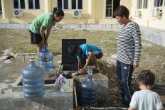 A boy (C) tries to get clean water from an underground water tank at a makeshift evacuation centre in Palu, in Central Sulawesi, on October 1, 2018, after an earthquake and tsunami hit the area on September 28. Mass graves were being readied on October 1 for hundreds of victims of the Indonesian quake and tsunami as authorities battled to stave off disease and reach desperate people still trapped under shattered buildings.  AFP/ Bay Ismoyo