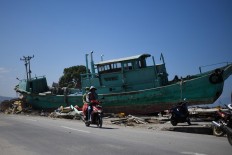Earthquake survivors ride past a boat on a street in Palu, Indonesia's Central Sulawesi on October 1, 2018, after an earthquake and tsunami hit the area on September 28. The death toll from the Indonesian quake-tsunami nearly doubled to 832 but was expected to rise further after a disaster that has left the island of Sulawesi reeling. AFP/Jewel Samad
