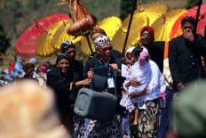 A young girl is shown a catfish stored in a bucket. JP/Maksum Nur Fauzan
