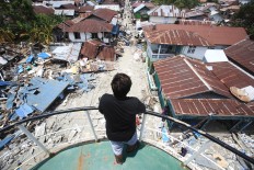 A member of the crew of the Sabuk Nusantara stands on his ship on Thursday, October. 4, 2018, the vessel was tossed onto the land in the tsunami at Wani Port in Donggala, Central Sulawesi. JP/Dhoni Setiawan