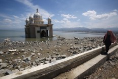 A survivor walks past the Arqam Baburahman Mosque at Talise Beach in Palu on Friday, October 5, 2018. The mosque was badly damaged in the quake and tsunami. JP/Dhoni Setiawan
