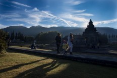 Visitors stick close together as they stroll through the Arjuna temple complex in the morning. JP/Tarko Sudiarno