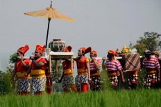 Male villagers dressed in traditional costumes carry clay water jugs and cone-shaped offerings on carts during the Syukuran Banyu (Thanksgiving for the Water) ceremony. JP/Magnus Hendratmo