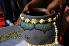A clay water jug is filled with water from the Pluneng water spring prior to the parade. JP/Magnus Hendratmo