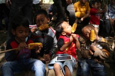  Four boys enjoy grilled corn at the market. JP/P.J.Leo