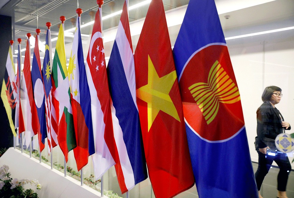 A woman walks behind flags at the ASEAN Summit at Suntec Convention Center in Singapore.