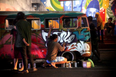 Spray time: Mural artists decorate a vintage car. JP/Maksum Nur Fauzan