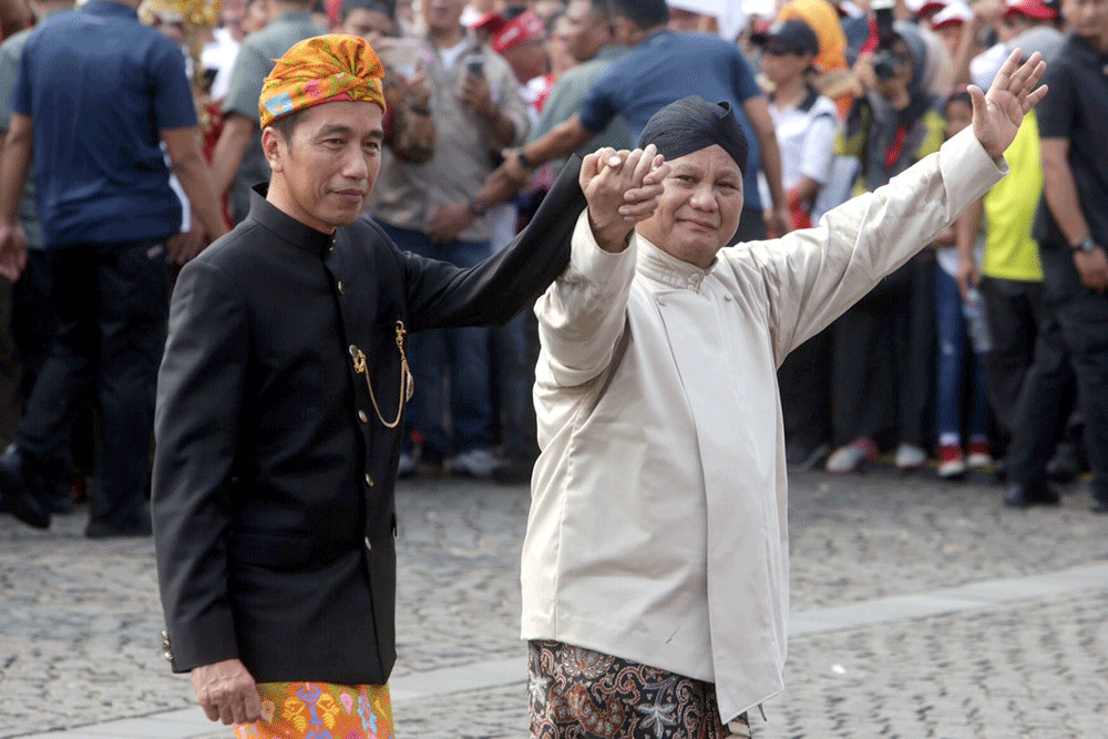 President Joko “Jokowi” Widodo (left) and his challenger Prabowo Subianto walk hand-in-hand during an event in Jakarta on Sept. 23, 2018.