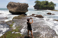 A tourist captures a moment at Madasari Beach. JP/Arya Dipa