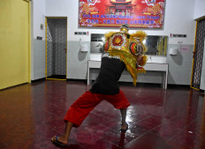 A young man practices in front of the mirror to coordinate the moves of the eyes and ears of the lion mask. JP/Aman Rochman
