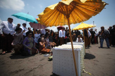 Begging to God: A senior woman royal servant leads a prayer in front of two boxes that will be cast into the sea. JP/Boy T Harjanto
