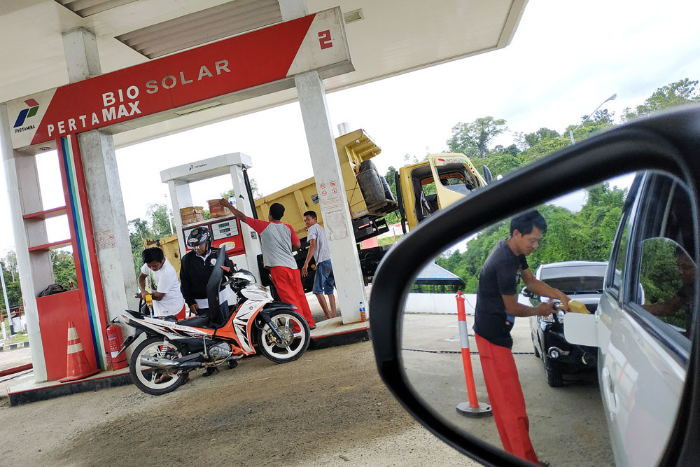 A gas station worker serves customers in the West Papua city of Bintuni in April 2019.
