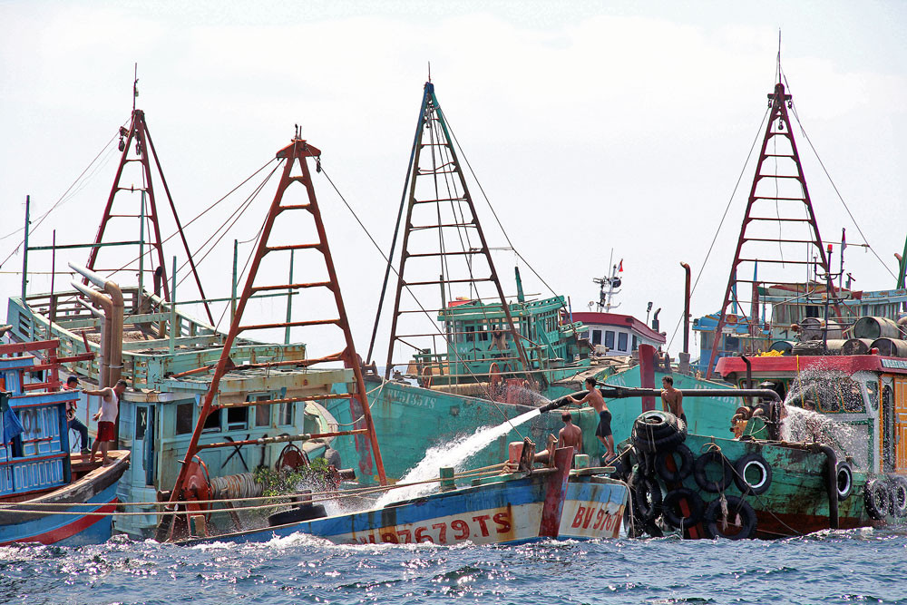 Workers sink Vietnamese fishing vessels by filling them with water after they were seized from fisherman fishing illegally in Indonesian waters near Datuk Island, West Kalimantan, on Saturday.