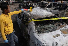 The National Police forensics unit inspects one of the burned cars. JP/Dhoni Setiawan