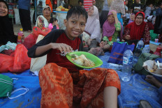 Recharged: A boy enjoys a serving of ketupat after playing at the beach. JP/ Zul Trio Anggono
