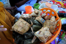 Balinese-style: A woman holds a basket of tipat (rice wrapped in palm leaves) and cylinder-shaped sticky rice known as bantal. Tipat and bantal, which symbolize feminine and masculine energies, often feature in traditional Balinese ceremonies. JP/ Zul Trio Anggono
