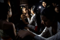 Balinese girls put on makeup as they prepare to perform the Sanghyang Dedari dance during the Api Wali Bhatara Sri ritual to honor the goddess of prosperity before the harvest time in Geriana Kauh village, Selat Duda, Karangasem regency.  JP/Agung Parameswara
